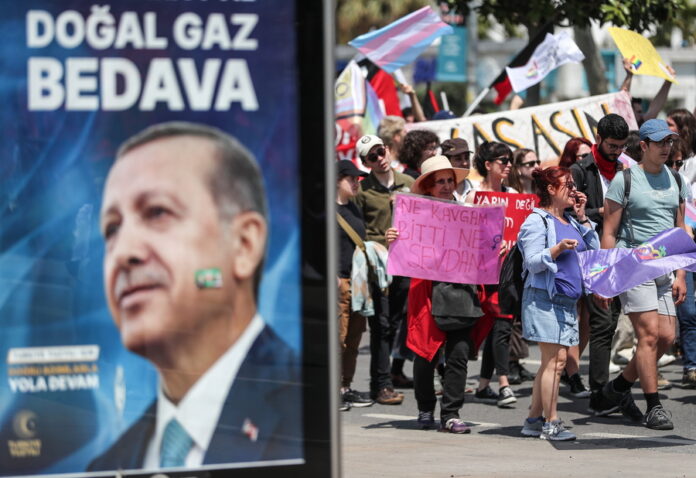 epa10601915 People hold placards and shout slogans near a picture of Turkish President Recep Tayyip Erdogan during a May Day celebration rally in Istanbul, Turkey, 01 May 2023. International Workers' Day is an annual holiday that takes place on 01 May and celebrates workers, their rights, achievements and contributions to society. EPA/ERDEM SAHIN